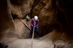 Guest rappelling down a deep slot canyon wall in Birch Hollow on a full-day East Zion canyoneering adventure.