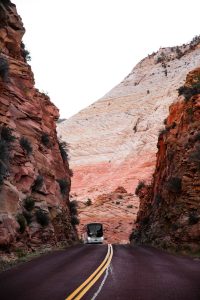 Commercial tour bus driving through the Zion-Mt. Carmel Tunnel switchbacks in Zion National Park.