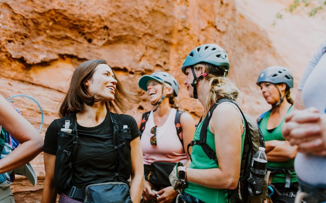 A diverse corporate group smiling at the exit of a technical slot canyon near Hurricane, Utah.