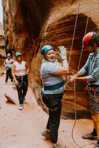 A professional worker after rappelling down a sandstone cliff during a corporate retreat near Zion National Park.