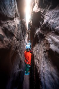 Guests on a Rock Odysseys guided canyoneering trip navigating a narrow slot canyon near Zion National Park.